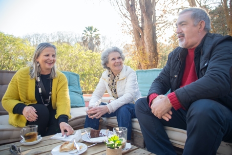 older aged people gathered outside sitting at a table talking