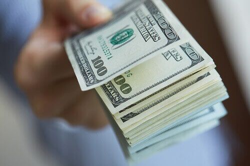 Close up of a hand holding 100 dollar bills.