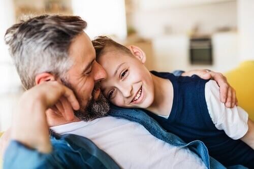 Smiling man sitting on a sofa holding a smiling boy.