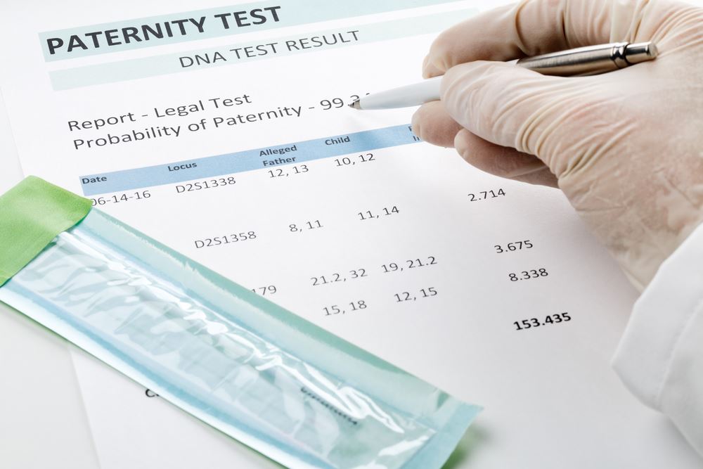 Close up of a gloved hand holding a pen above a paternity test.