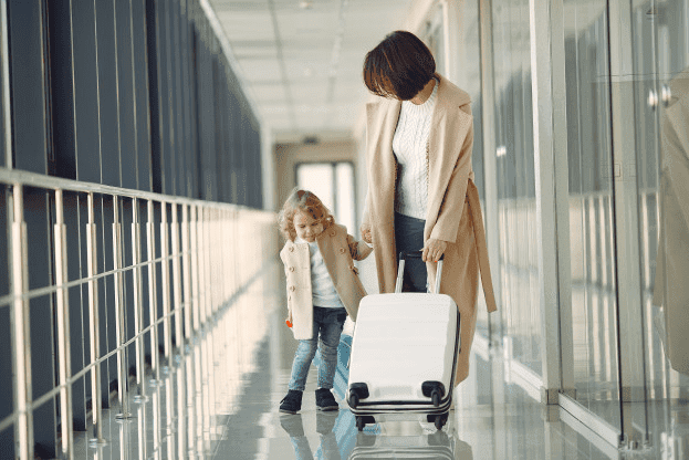 A woman holding luggage and walking with a young girl in an airport.